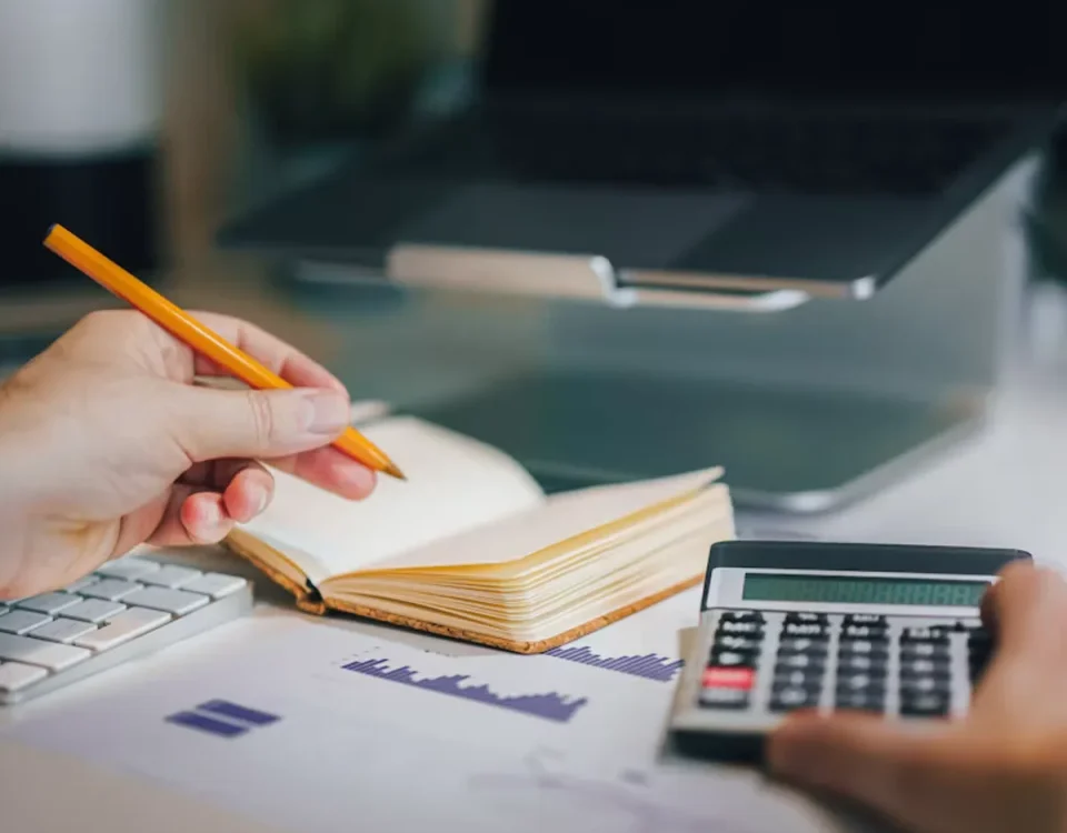 Profissional com calculadora e caderno na mesa