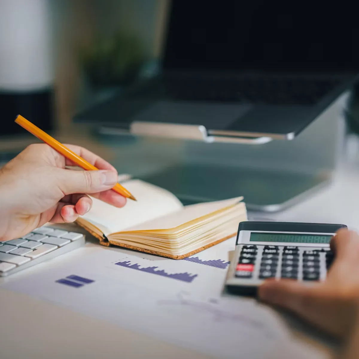 Profissional com calculadora e caderno na mesa